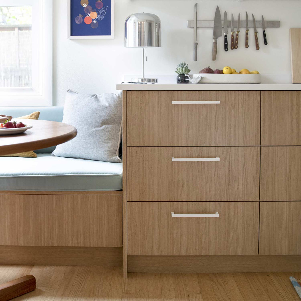 Front view of Edgecliff appliance pull showcasing its white bar design on wood cabinetry in a bright kitchen