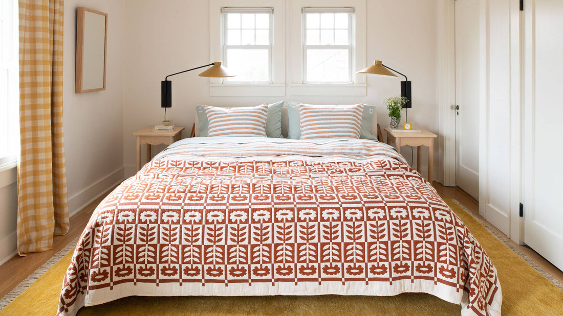 Two mustard plug-in wall sconces mounted above bedside tables in a sunlit bedroom with rust-and-white quilt
