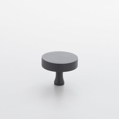 Elevated front view of Riverwood Knob in True Black showcasing its flat finish and fluted neck on a light gray background