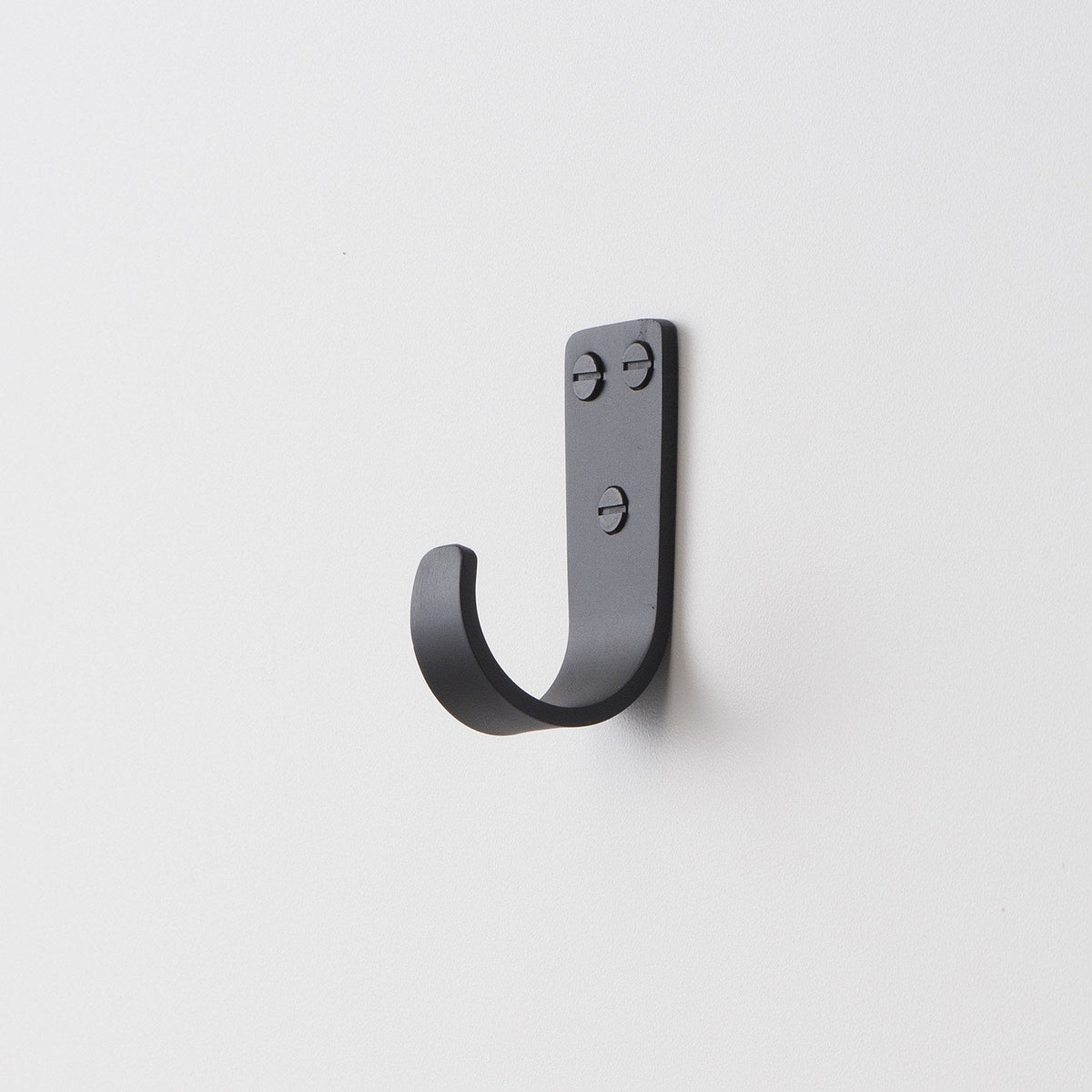 Angled close-up of Thomas Hook showing J-shaped metal hook with exposed screw heads on a white wall