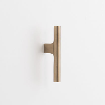 Front view of Galley Pull showcasing asymmetrical intersecting curves in natural brass on a white background