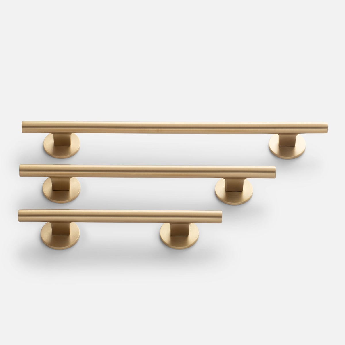 Front view of three natural brass Galley Pulls showcasing round backplates and different lengths on a white background