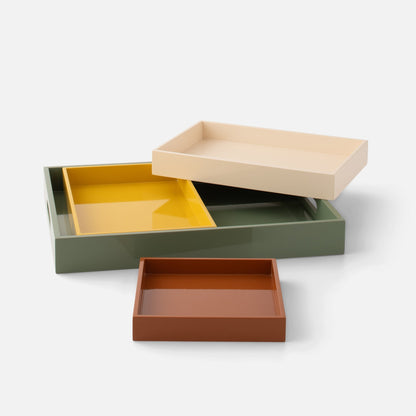 Angled view of Stacking Trays, Set of 4 showcasing four nesting lacquered trays in muted colors on a white background