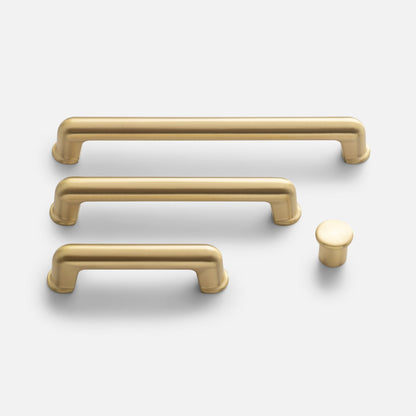 Front view of the Remy Knob and matching pulls showcasing soft curves and solid brass construction on a white background