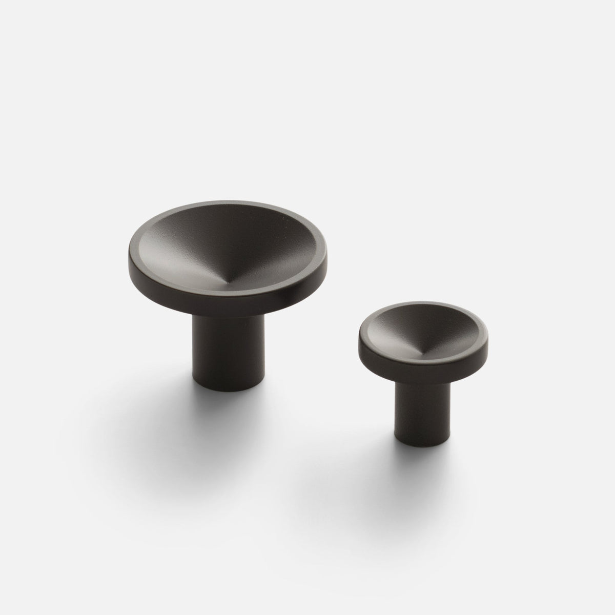 Close-up of two Rhone Knob sizes showcasing textured recessed faces and cylindrical stems on a white background