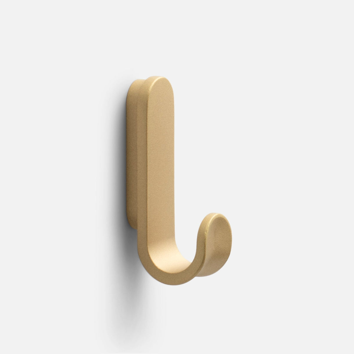 Front three-quarter view of the Rhone Hook showcasing its Cast Brass finish and curved minimalist design against a light gray background