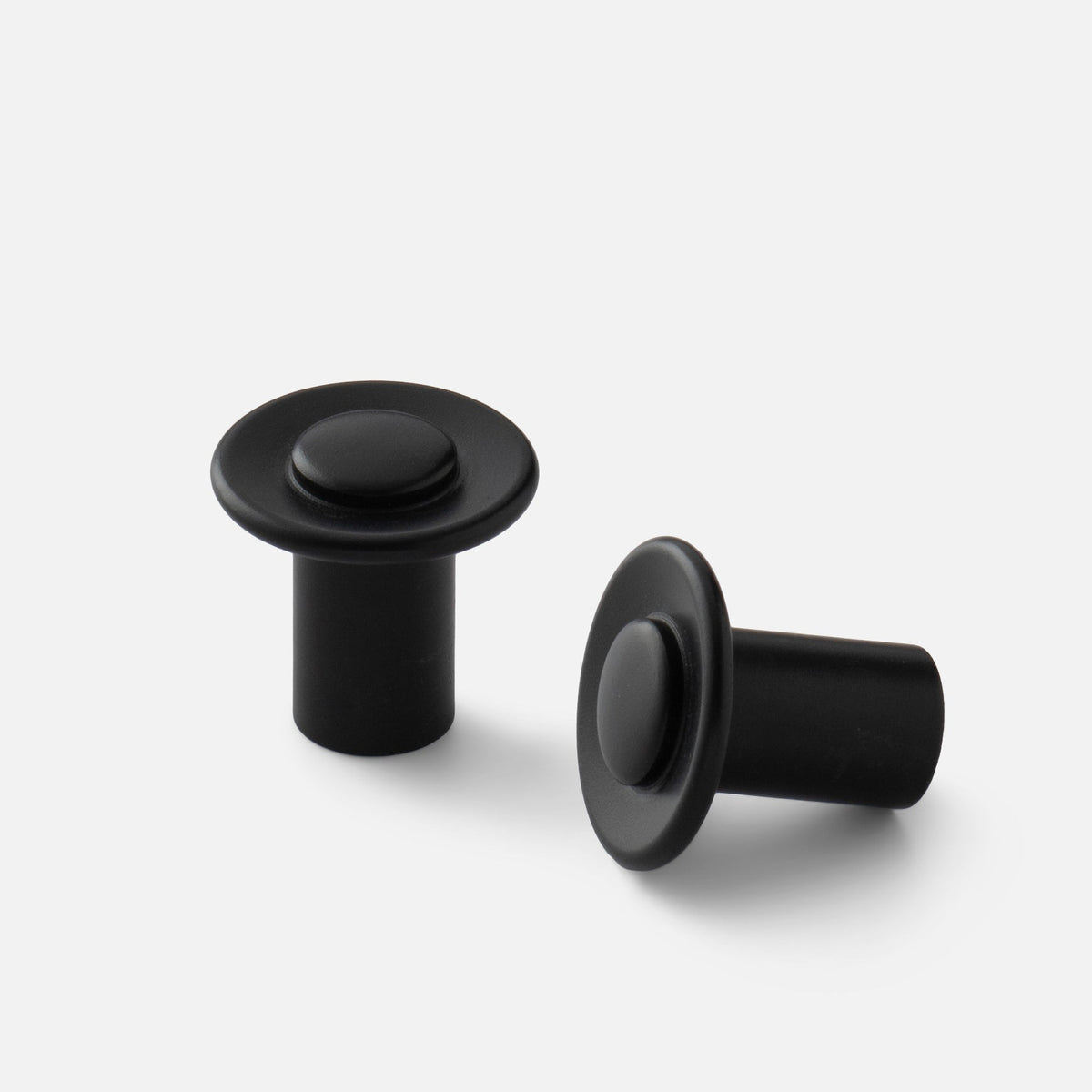 Front and side views of black Landon knobs showcasing round faces and cylindrical bases on a white background