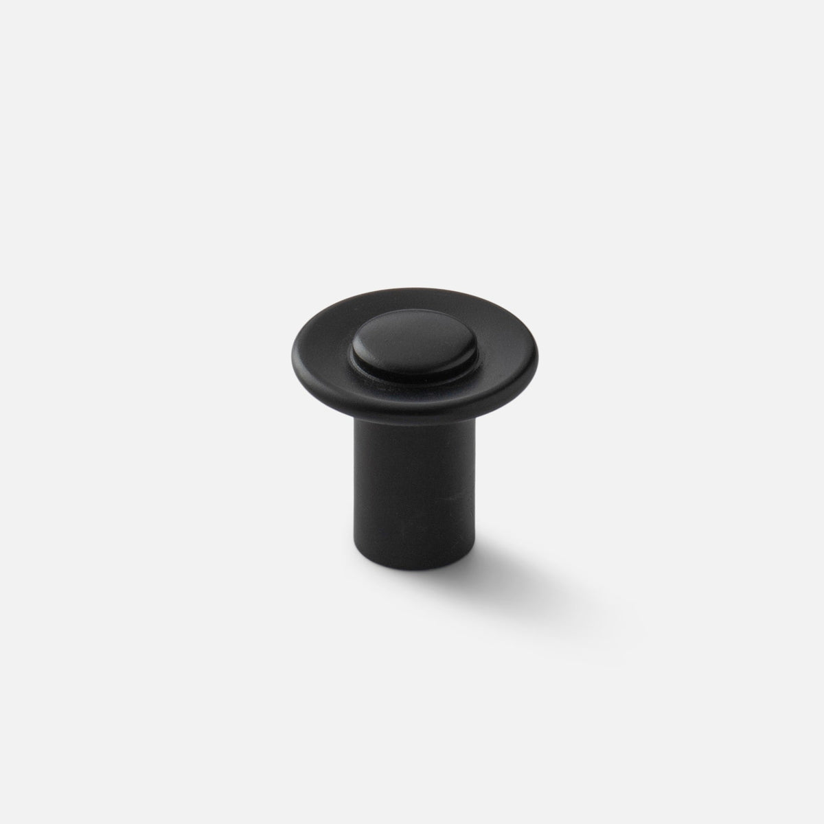 Front three-quarter view of Landon Knob showcasing its black round face and cylindrical base on a light gray background