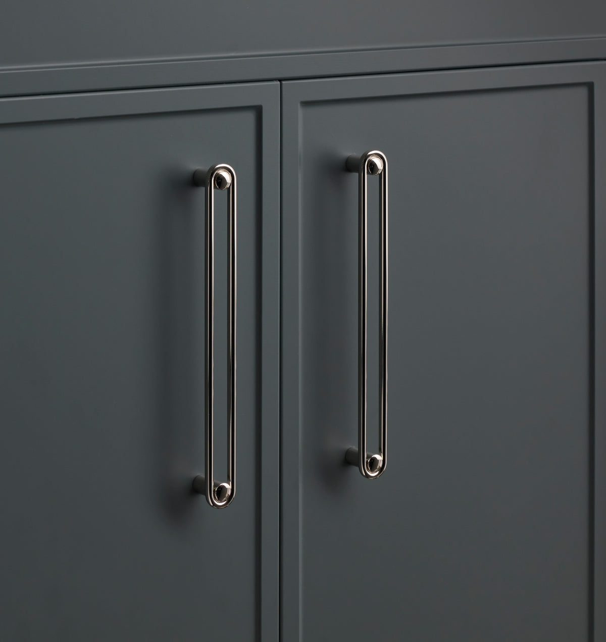 Close-up of two Landon Pull cabinet handles showcasing elongated rounded ends on dark cabinet doors