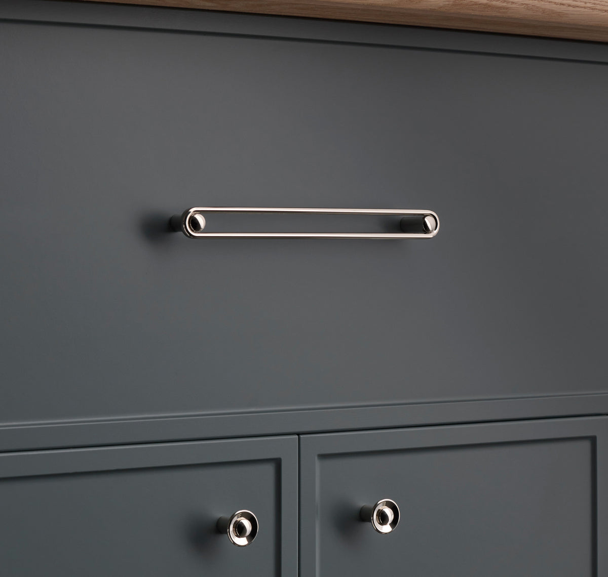 Front view of Landon Pull showcasing an elongated reflective bar mounted on a dark gray cabinet