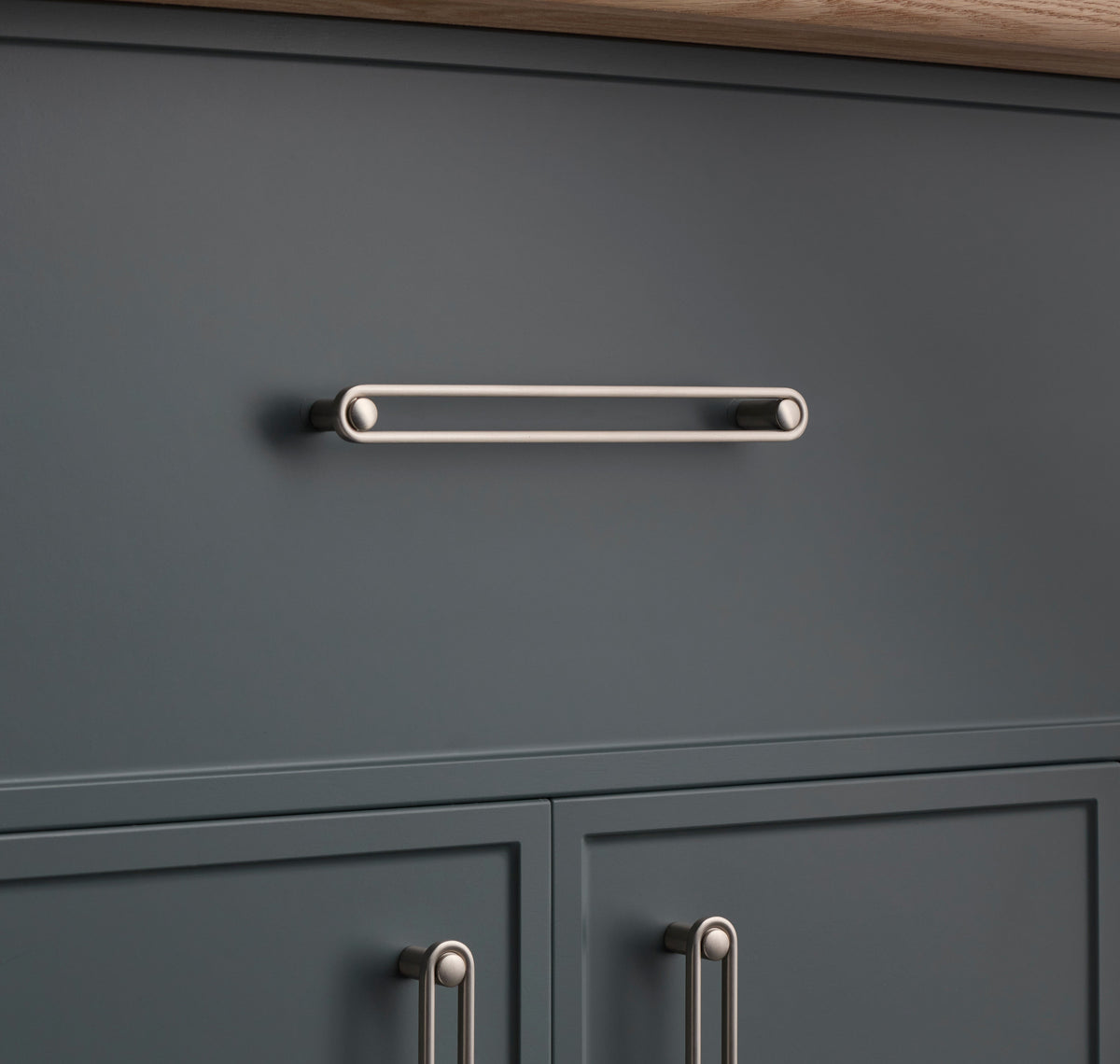 Front view of Landon Pull showcasing an elongated bar with rounded ends on a dark gray cabinet
