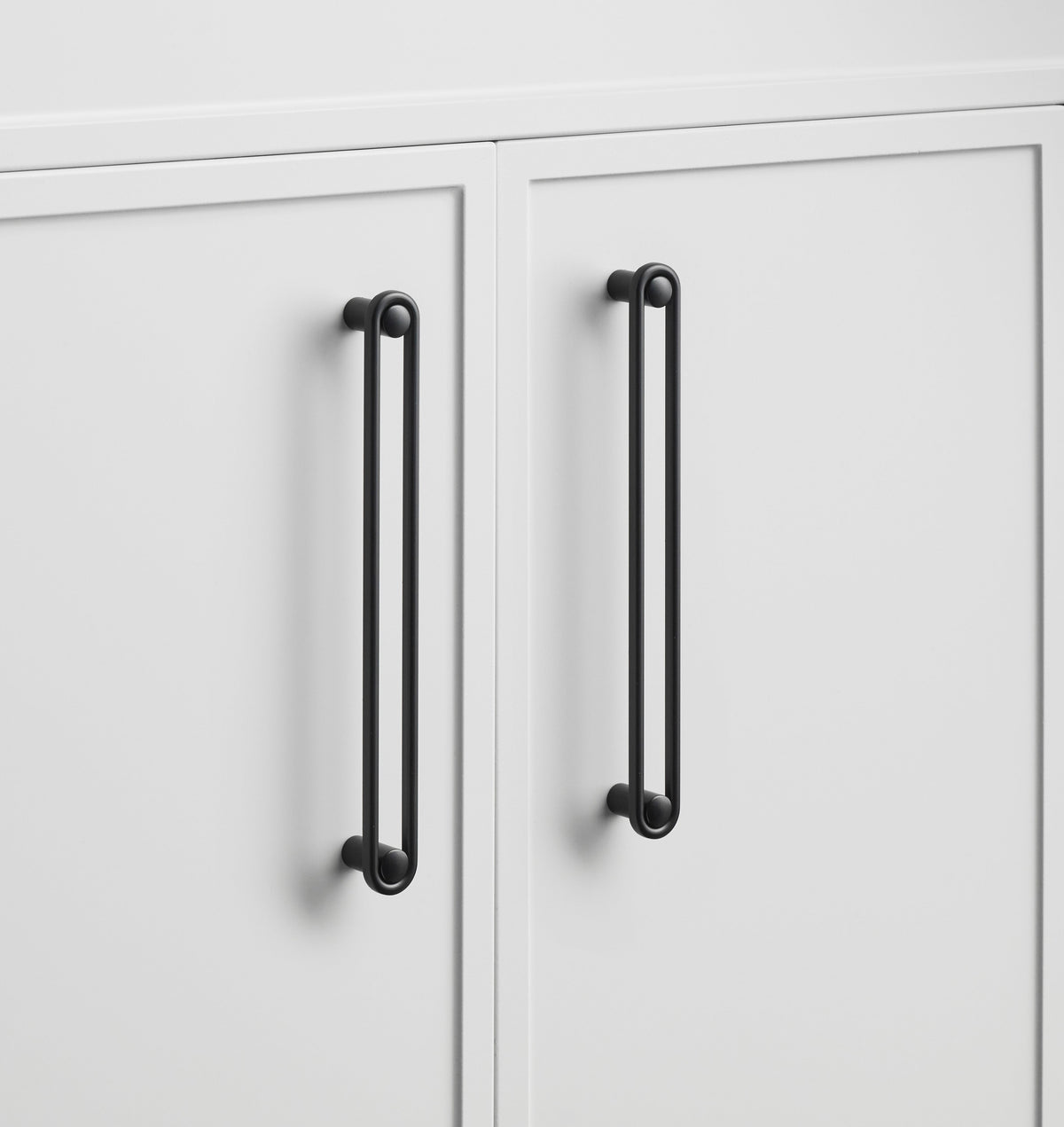 Close-up of Landon Pull showcasing its elongated black bar design on white cabinet doors