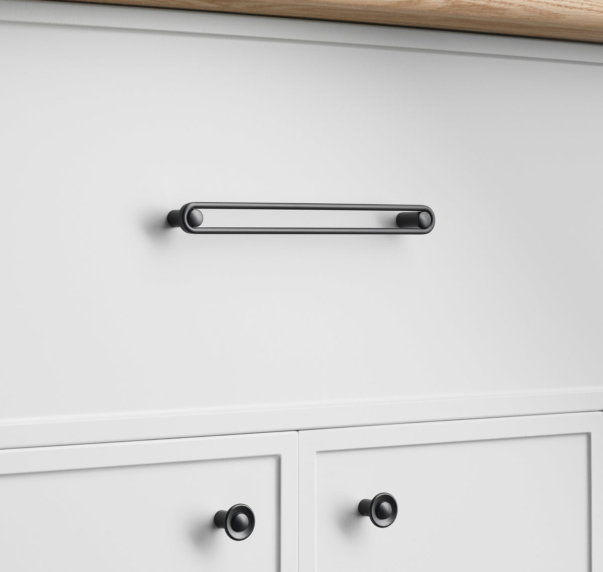 Front view of Landon Pull showcasing its rounded rectangular bar and circular end caps on white cabinetry