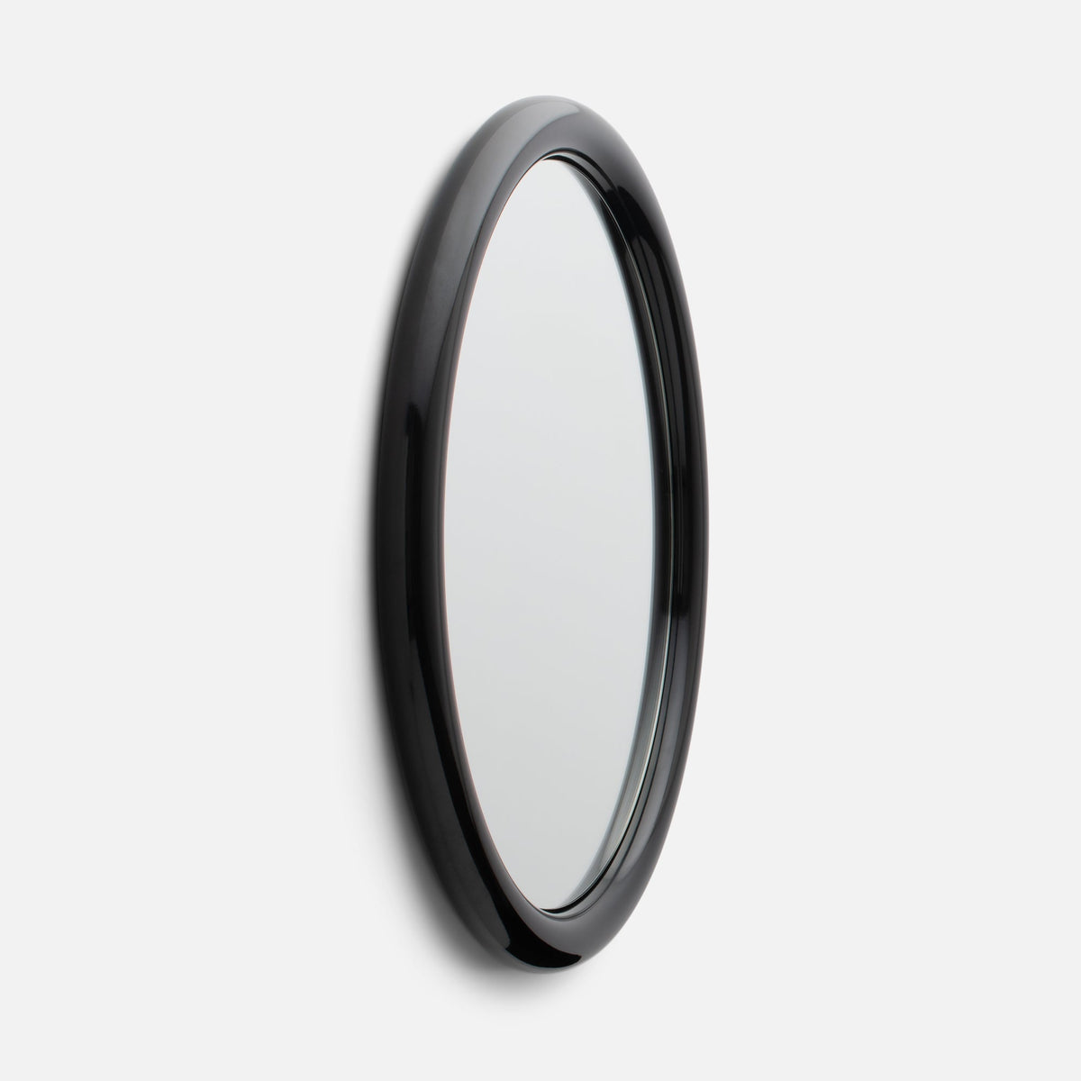 Close-up side view of Forma Mirror showcasing its glossy black rounded frame and beveled edge against a white wall
