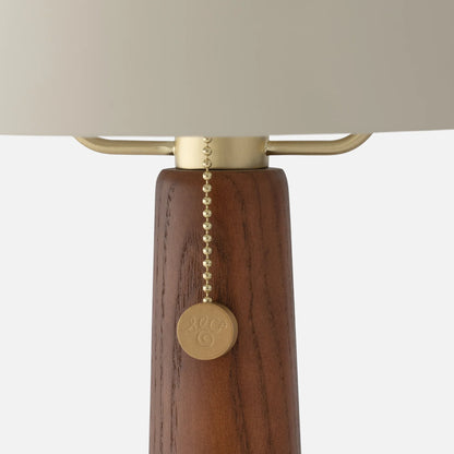 Close-up of Evelyn Table Lamp showcasing wood stem and brass pull chain on a white background