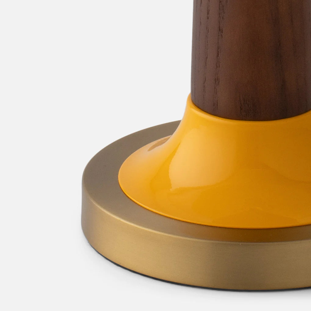 Close-up view of Evelyn Table Lamp showcasing yellow gloss-painted metal and brass base with walnut stem on white background