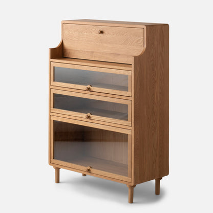 Front three-quarter view of Peggy Cabinet showcasing a wood finish, upper drawer, and three glass-front compartments on a white background
