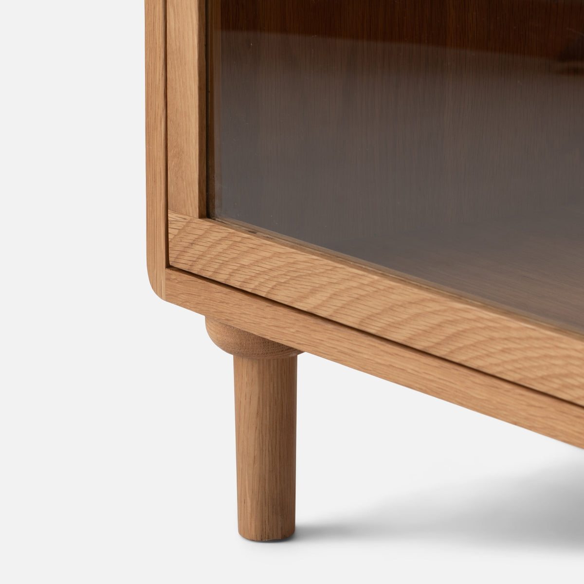 Close-up of Peggy Cabinet showcasing rounded wood frame, dark inset panel, and cylindrical leg on white background