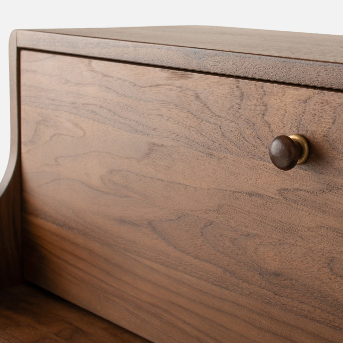 Close-up view of Peggy Cabinet showcasing wood grain, rounded edges, and a dark round knob with brass hardware