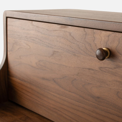 Close-up view of Peggy Cabinet showcasing wood grain, rounded edges, and a dark round knob with brass hardware