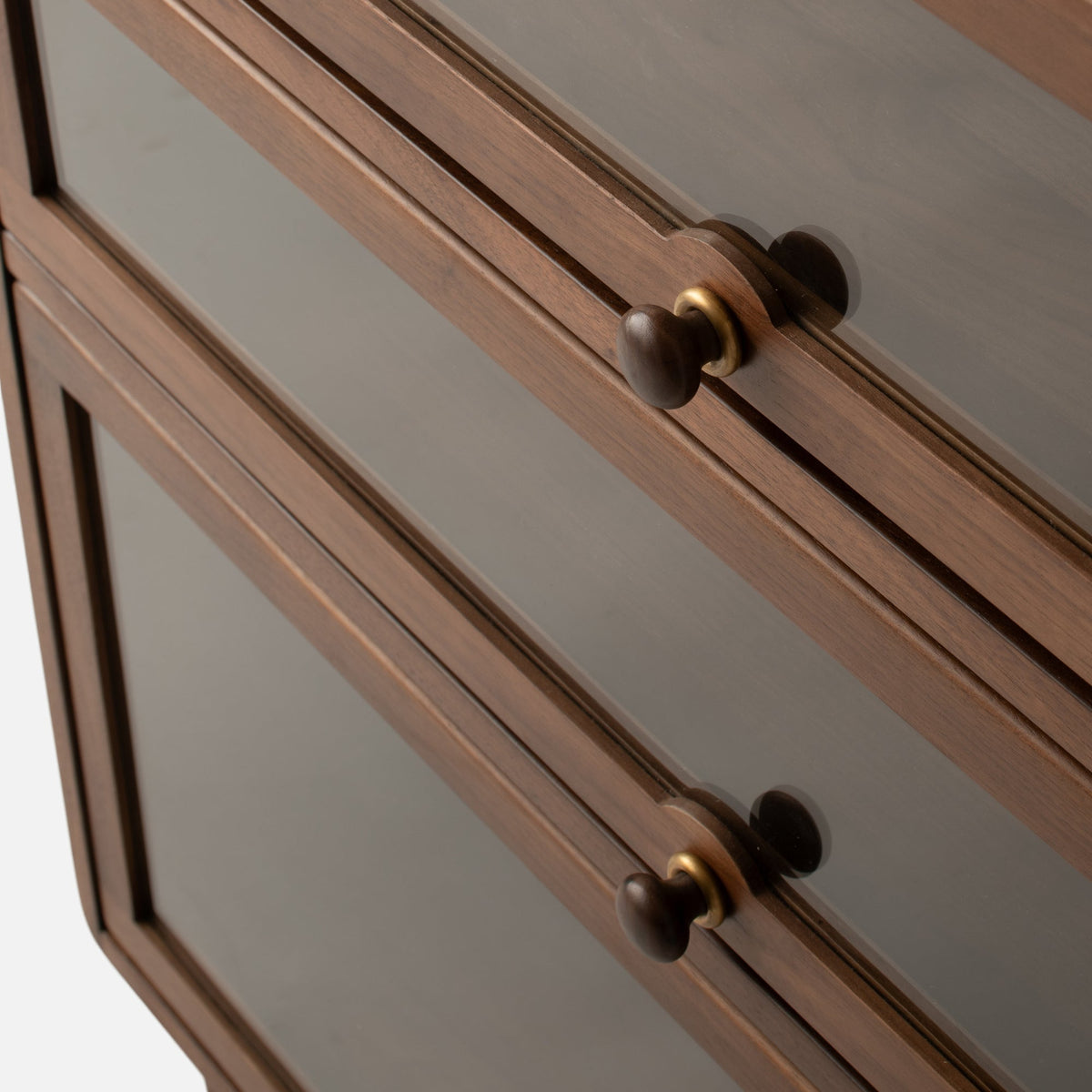 Close-up view of Peggy Cabinet showcasing brown wood framing, gray inset doors, and dark knobs with brass rings