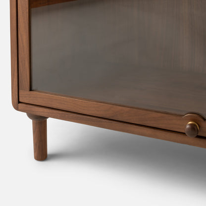Close-up front view of Peggy Cabinet showcasing wood-grain frame, glass door, and round knob on white background