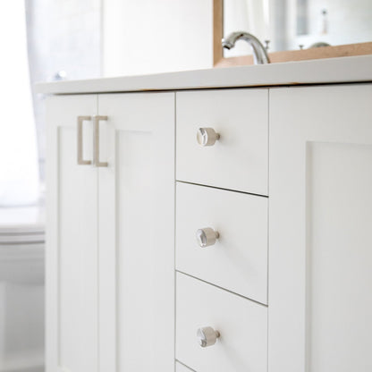 View of Edgecliff Pulls installed on white bathroom vanity drawers with faceted cylindrical fronts