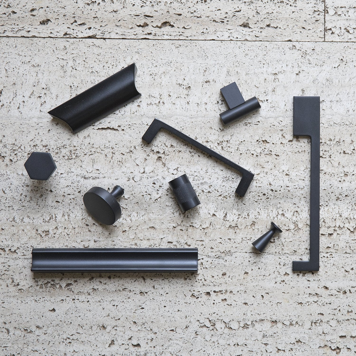 Overhead view of the True Black Radcliffe Knob showcasing solid brass construction with coordinating hardware on a textured stone surface