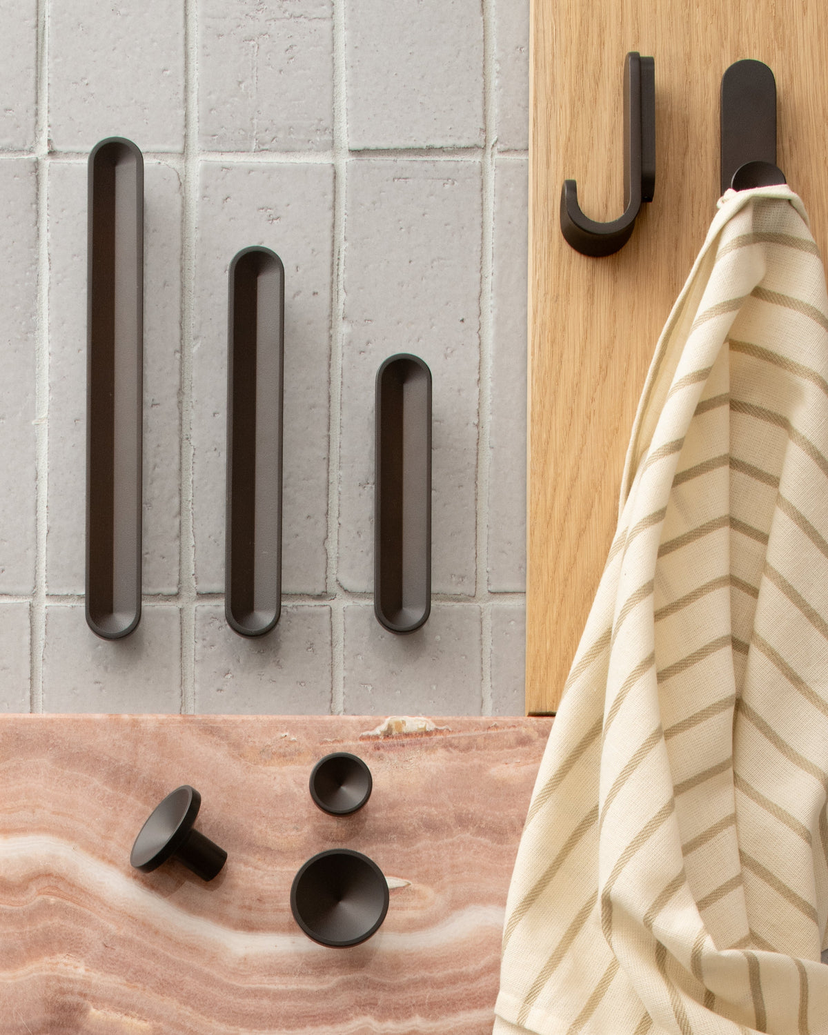 Front view of Rhone Hook showcasing its minimalist curved design with tile, wood, and a striped towel background
