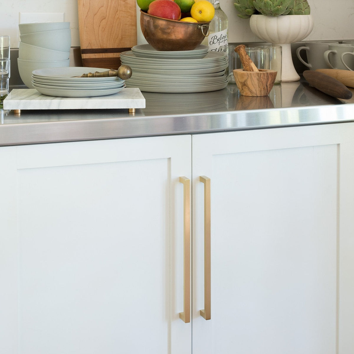 Front view of Edgecliff appliance pulls showcasing their long brass finish on white kitchen cabinets