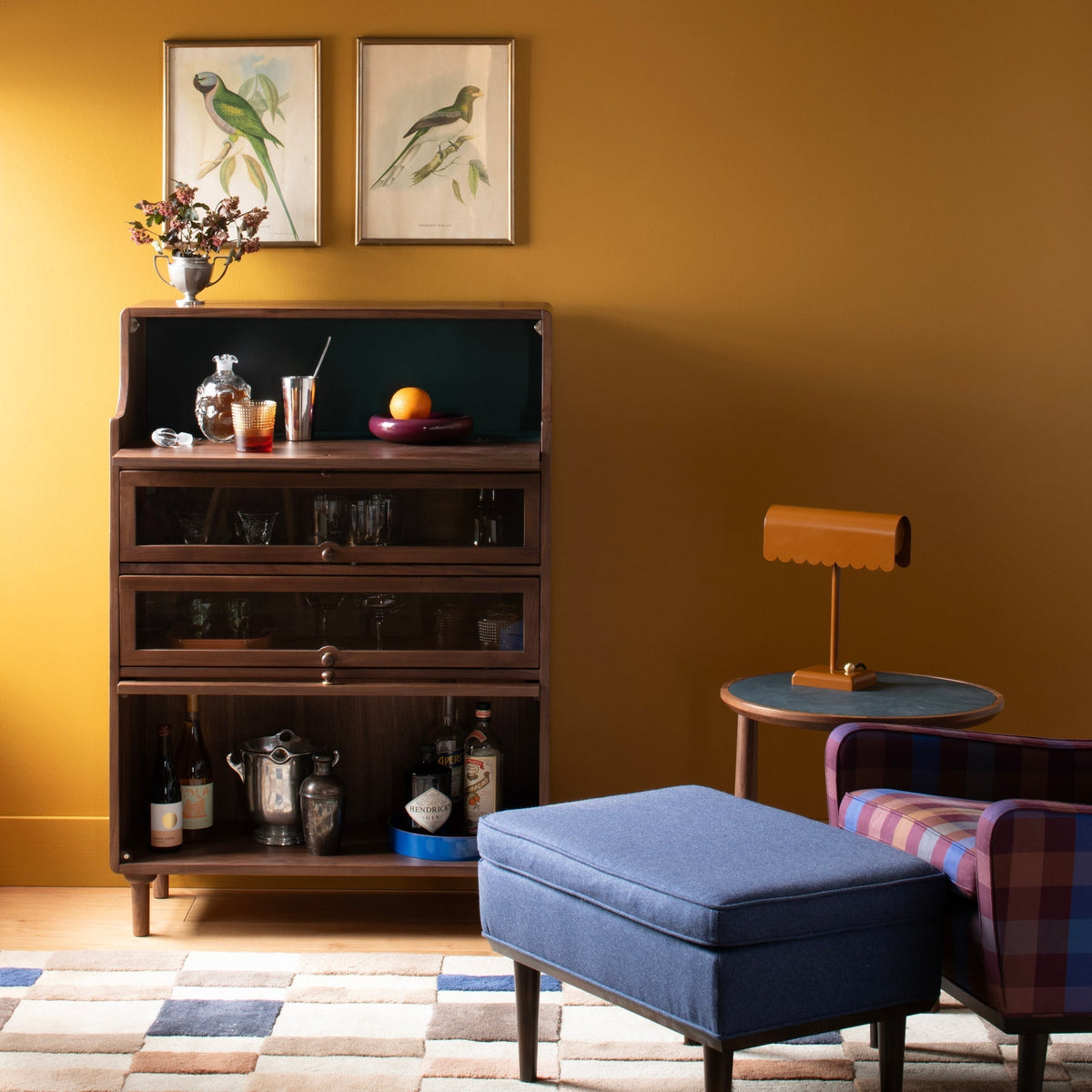 Front view of Peggy Cabinet showcasing dark wood, glass-front doors, drawers, and open shelving in a living room setting