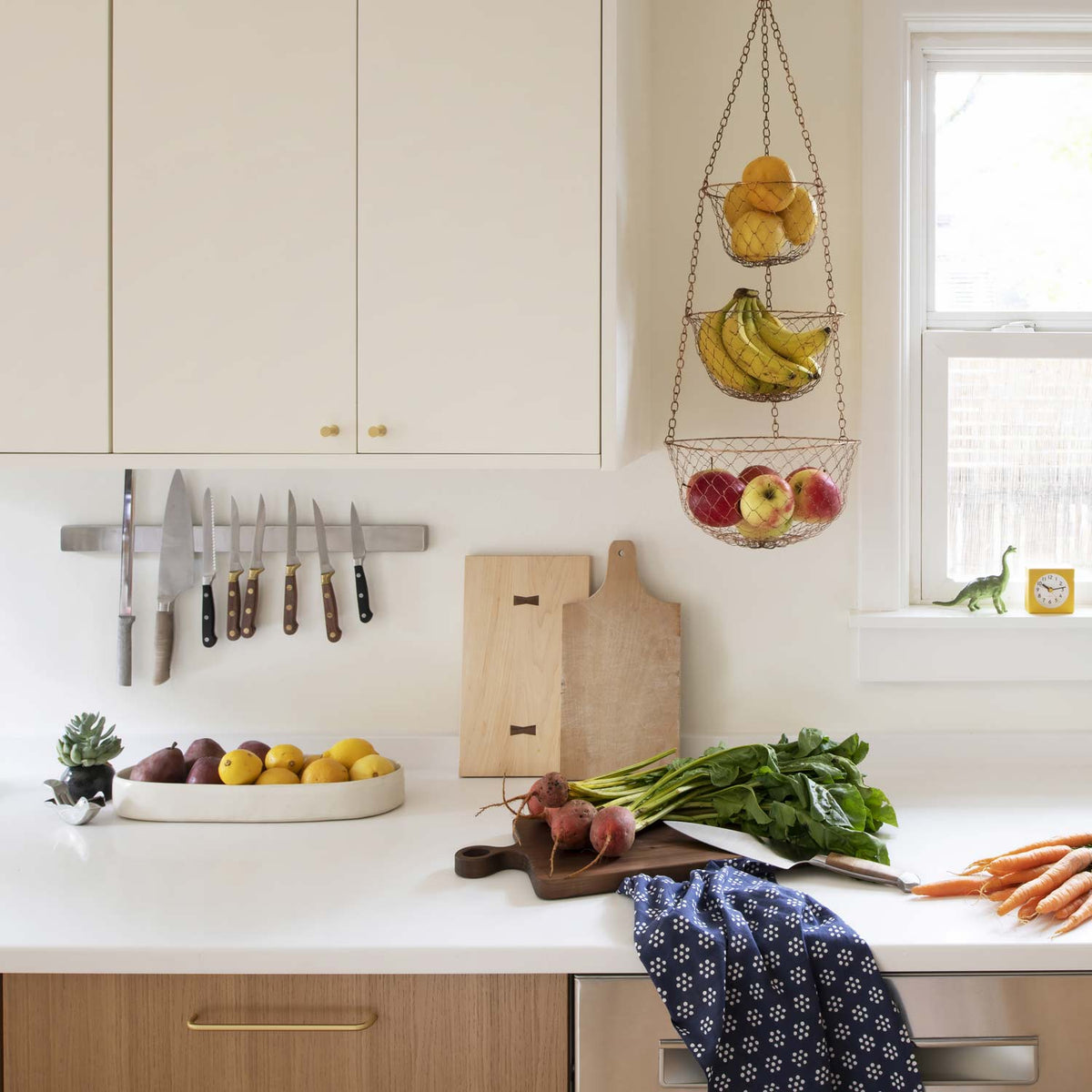 Parker Pull installed on a kitchen cabinet in a bright kitchen with a hanging fruit basket and fresh produce