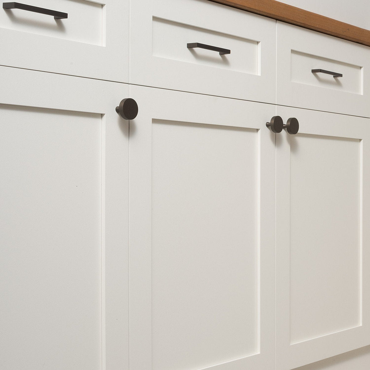 Riverwood knobs installed on white paneled cabinet doors alongside matching bar pulls