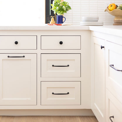 Somerset appliance pulls installed on white kitchen cabinets in a bright kitchen