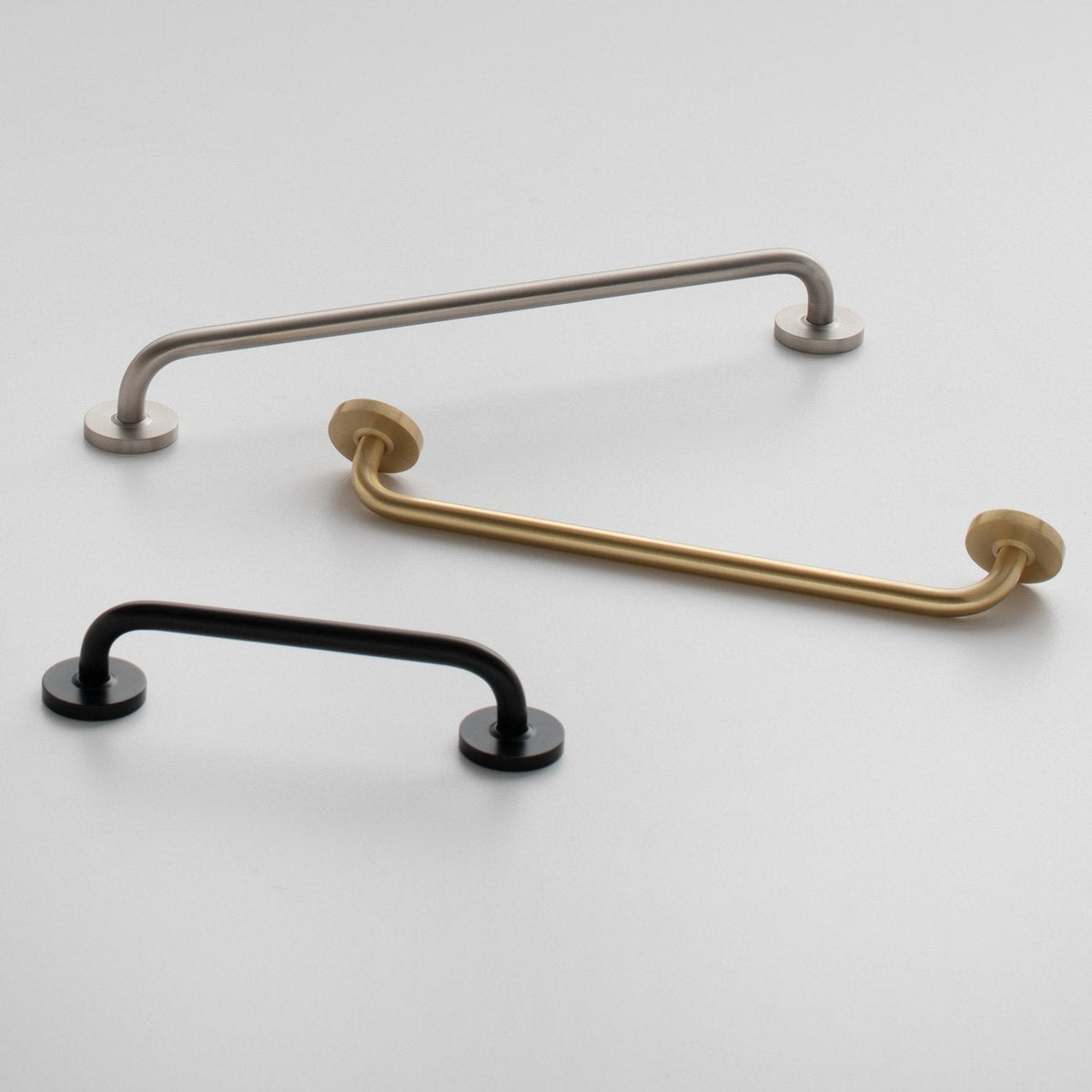 Overhead view of Parker Pull showcasing curved bar designs in silver, brass, and black on a light background