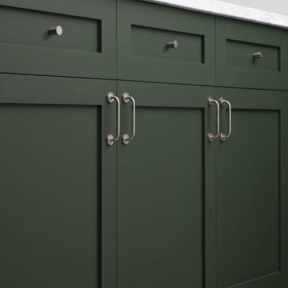 Close-up of Parker Pull cabinet handles showcasing curved metal design with dark green cabinetry
