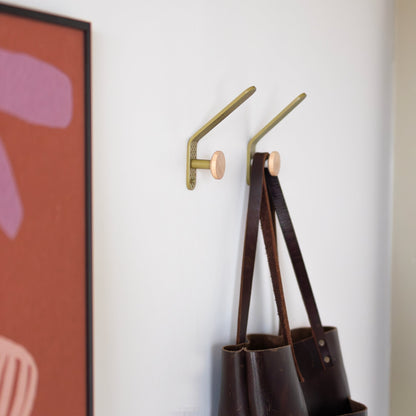 Tula hooks holding tote bags on a white wall beside framed artwork