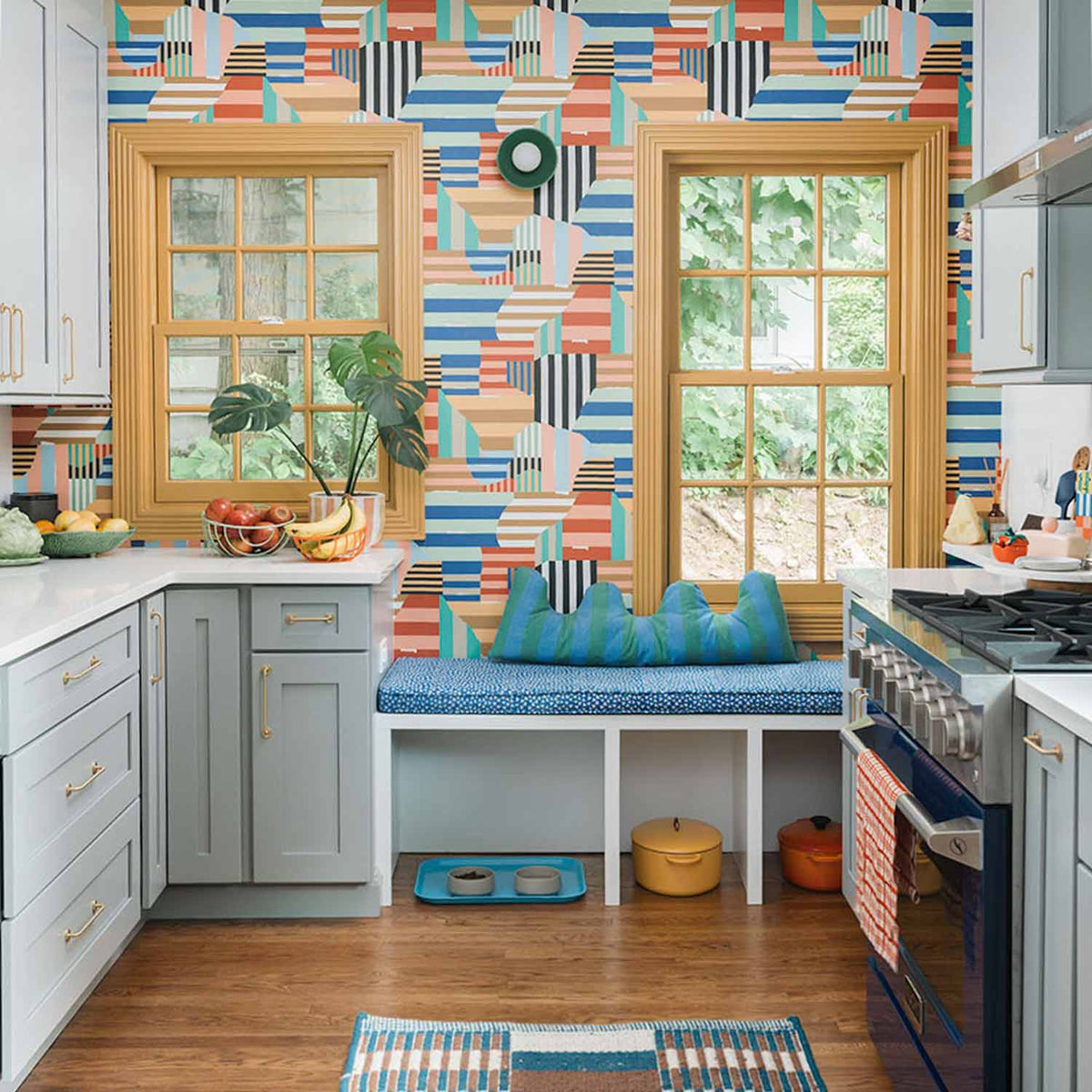 Kitchen featuring gold cabinet pulls, colorful geometric wallpaper, windows, and a built-in bench