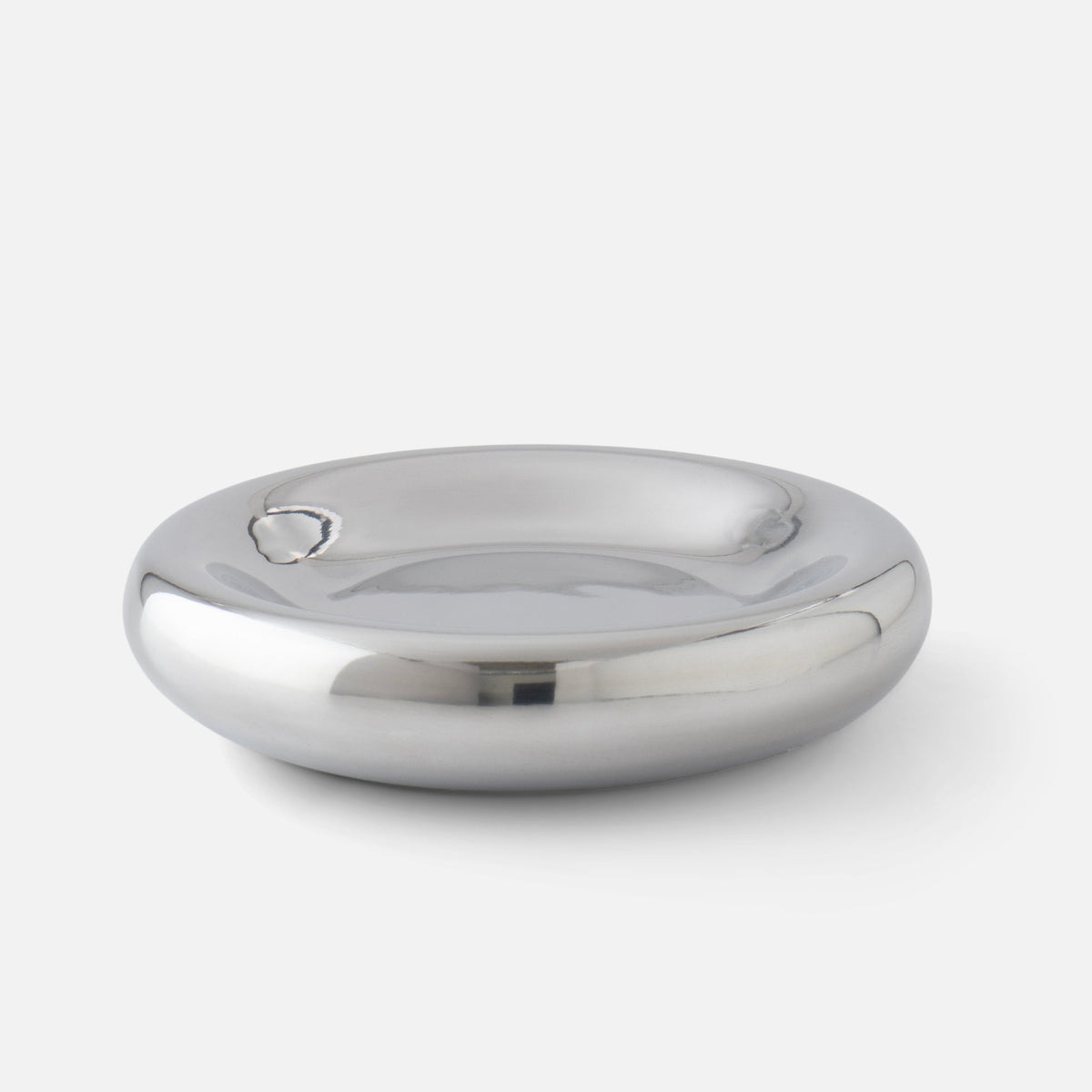 Close-up of Yves cast metal catchall showcasing polished mirrored finish and rounded shallow bowl on white background