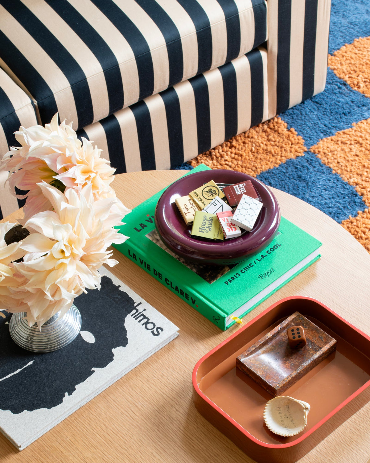 Close up of Raisin Yves cast metal catch all showing glossy rim on a book on a wood table with striped ottoman and rug