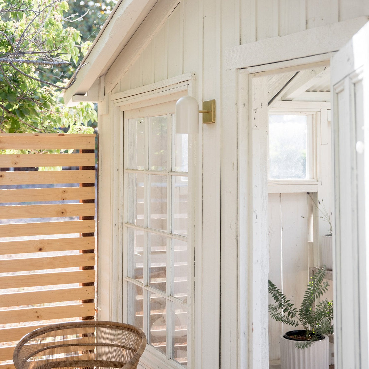 White Allegheny 4.5-inch sconce mounted on a white siding wall beside a glass‑paned door on a sunlit porch