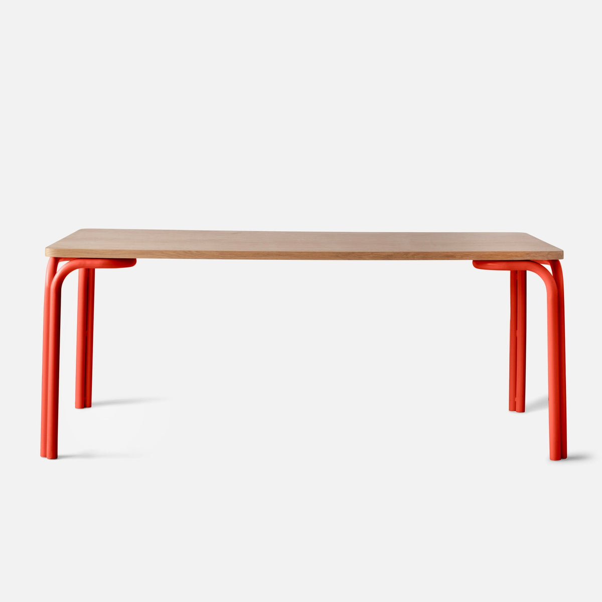 Front view of Forma Dining Table showcasing light oak tabletop and red tubular metal legs on white background